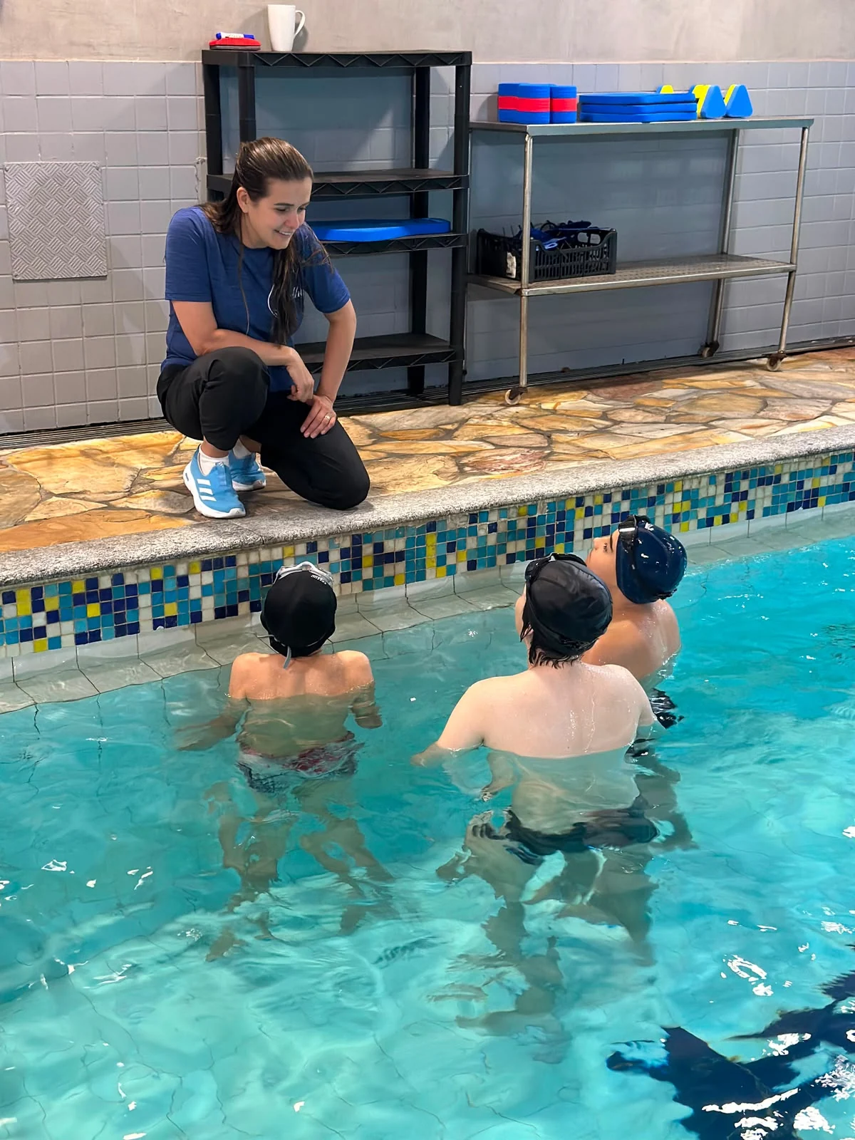 Professora orientando alunos na piscina